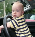A baby boy plays with car steer